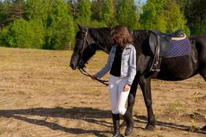 Woman is walking a horse in a field photo