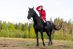 Woman is riding a black horse in a field photo