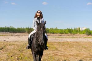 Woman is riding a horse in a field photo