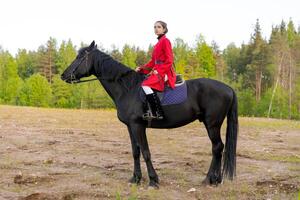 Woman is riding a black horse in a field photo