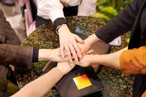 Group of people are holding hands in a circle on a table photo