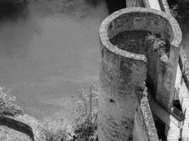A black and white photo of a tower with a bridge over a river