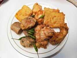 photo of a typical Indonesian snack plate consisting of fried tofu, fried tempeh, bakwan and fried banana placed on a white plate