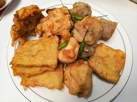 photo of a typical Indonesian snack plate consisting of fried tofu, fried tempeh, bakwan and fried banana placed on a white plate