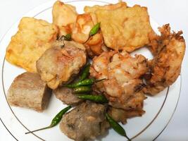 photo of a typical Indonesian snack plate consisting of fried tofu, fried tempeh, bakwan and fried banana placed on a white plate