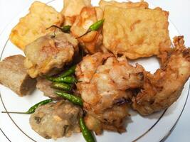 photo of a typical Indonesian snack plate consisting of fried tofu, fried tempeh, bakwan and fried banana placed on a white plate