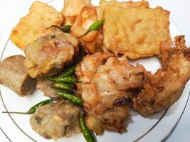 photo of a typical Indonesian snack plate consisting of fried tofu, fried tempeh, bakwan and fried banana placed on a white plate