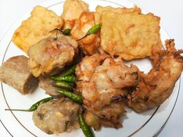 photo of a typical Indonesian snack plate consisting of fried tofu, fried tempeh, bakwan and fried banana placed on a white plate