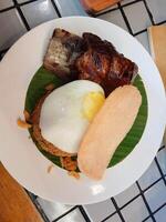 fried rice with grilled ribs and sunny side up egg on top and prawn crackers as a complement photo