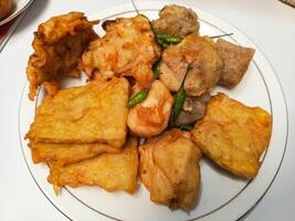 photo of a typical Indonesian snack plate consisting of fried tofu, fried tempeh, bakwan and fried banana placed on a white plate