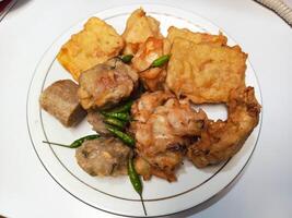 photo of a typical Indonesian snack plate consisting of fried tofu, fried tempeh, bakwan and fried banana placed on a white plate