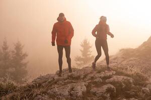trail running couple man and woman running on a mountain path photo