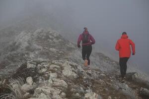 trail running couple man and woman running on a mountain path photo