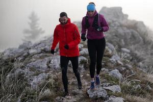 trail running couple man and woman running on a mountain path photo