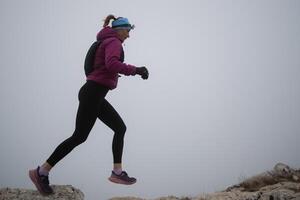 sky running or trail running woman exercising on a mountain top photo