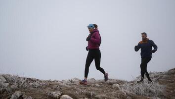 trail running couple man and woman running on a mountain path photo