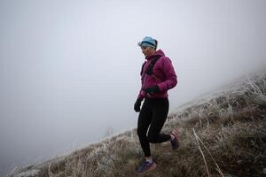 trail running woman athlete training for ultra-marathon race in a mountain photo