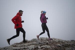 Athlete couple trail running on the mountain top in the early morning. Sky running concept photo
