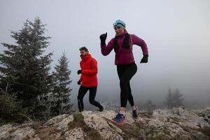 trail running couple man and woman running on a mountain path photo