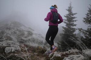 trail running woman athlete training for ultra-marathon race in a mountain photo