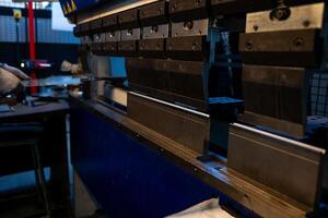 Worker prepares a metal sheet on an industrial press machine, focusing on precision in a factory environment. photo