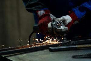 Craftsman using an angle grinder, creating bright sparks while working on a metal frame in the workshop. photo