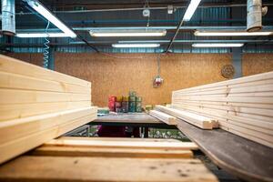 A workbench in a woodworking factory, with wooden beams and tools ready for processing under bright fluorescent lights photo