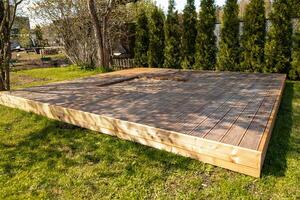 Wooden deck with central sandpit in a backyard setting, surrounded by trees and natural surroundings photo