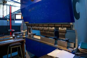Worker prepares a metal sheet on an industrial press machine, focusing on precision in a factory environment. photo