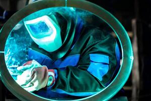 Focused welder creating strong welds on a circular metal piece, sparks flying around in the workshop. photo