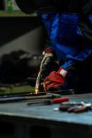 Worker in protective gear handling a welding torch, intense light and sparks flying in the workshop. photo
