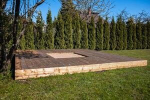 Wooden deck with a central sandpit in a sunny backyard, featuring a clean and simple design photo
