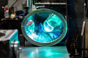 Focused welder creating strong welds on a circular metal piece, sparks flying around in the workshop. photo