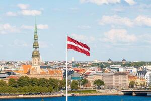 Latvian national flag waving with old Riga cityscape in the background photo