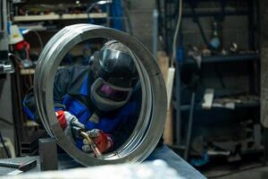 Welder skillfully working on a large metal ring, carefully welding joints in a well equipped workshop. photo