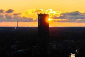 Aerial view of Riga at sunset, featuring the Daugava River, bridges, and historic buildings under a warm orange sky. photo