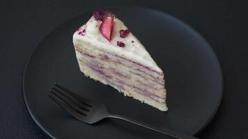 Piece of sweet layer cake with white cream, raspberries and strawberries on a dark concrete background video