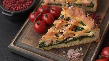 Pieces of quiche with salmon, spinach or broccoli, salt and spices on a dark concrete background video