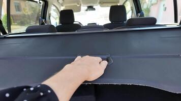 Hand pulling trunk cover inside car, symbolizing travel readiness and road trip adventures video