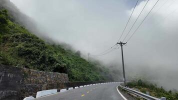 Foggy mountain road with lush greenery and power lines ideal for travel or nature themes video