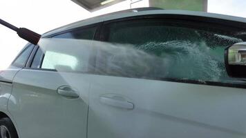A white car is being pressure washed at a car wash, symbolizing cleanliness and maintenance video