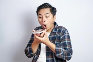 Happy asian funny man standing while on phone with loud speaker mode. Isolated on white background photo