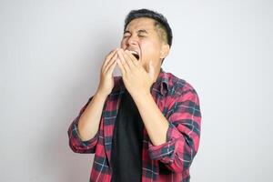 A Southeast Asian man sneezing while holding his nose. Captures a moment of discomfort, suitable for themes related to health, allergies, or cold symptoms in various marketing or editorial contexts photo