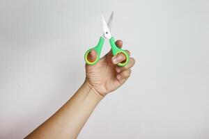 Hand holding a green scissors on white background photo