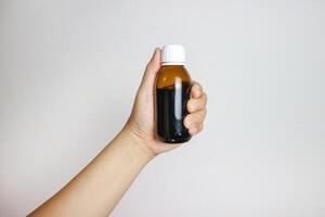 Hand holds an amber glass vitamins, supplements and minerals dual layer tablets pills and medicine bottle to show or see the label on white background. There is copy space on the label. Blank label. photo