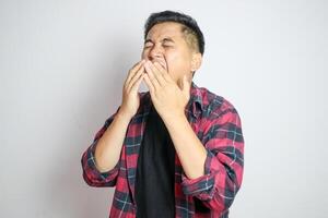 A Southeast Asian man sneezing while holding his nose. Captures a moment of discomfort, suitable for themes related to health, allergies, or cold symptoms in various marketing or editorial contexts photo