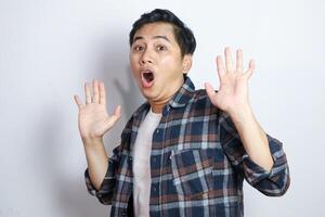 Excited Asian man gasping with hands open and looking to copy space isolated on white background photo