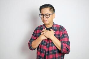 hand hold chest with heart attack symptoms, asian man working hard have chest pain caused by heart disease, leak, dilatation, enlarged coronary heart, press on the chest with a painful expression photo