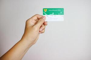 Hand holding Indonesian Government Health Insurance Card or Kartu BPJS Kesehatan isolated on white background, Magelang-Indonesia, 16-07-2023 photo