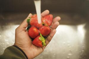 Thoroughly Hand Washing Fresh Strawberries Under Running Water for Optimal Cleanliness photo